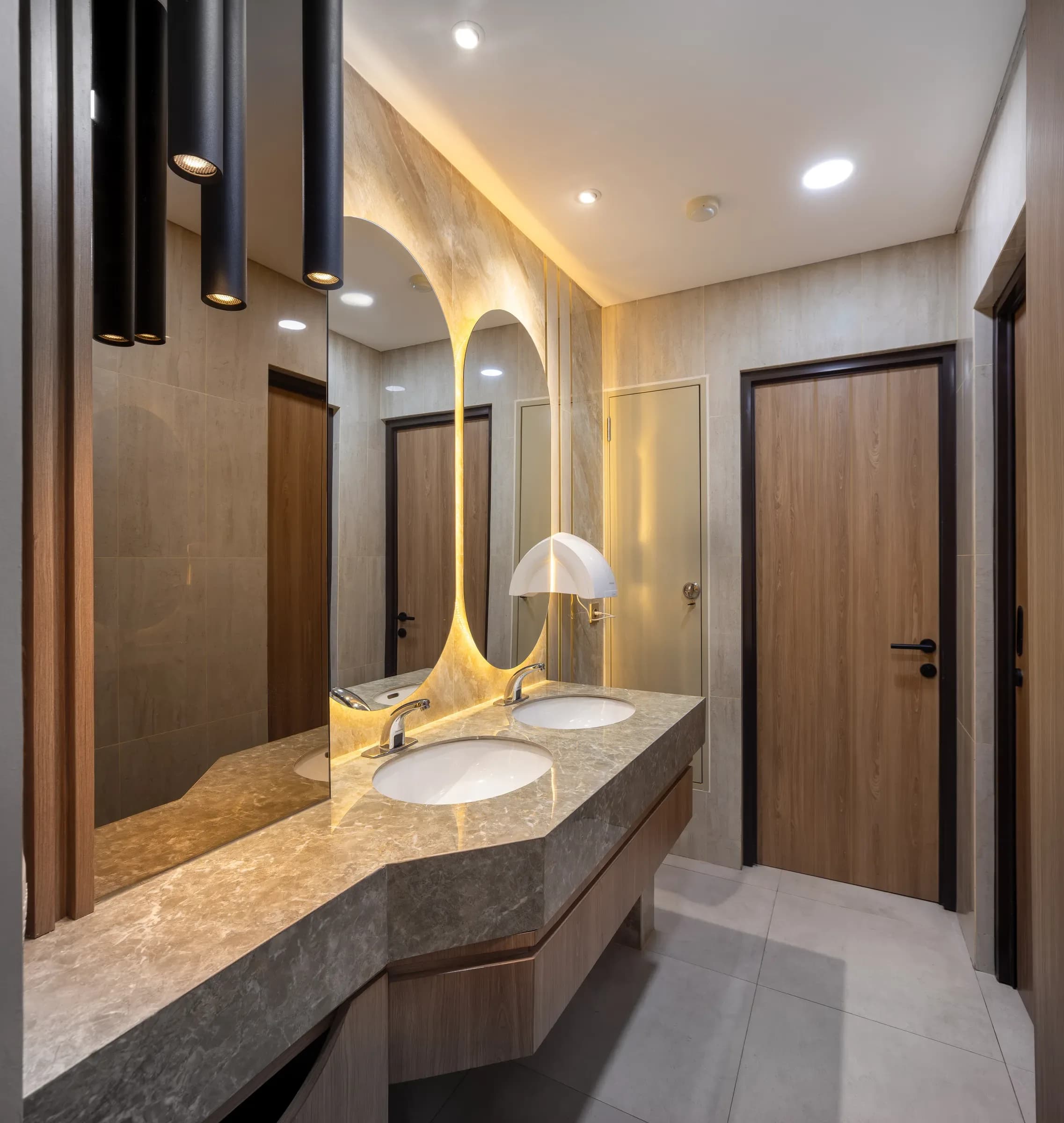 Washroom with a stone vanity and arched backlit mirrors