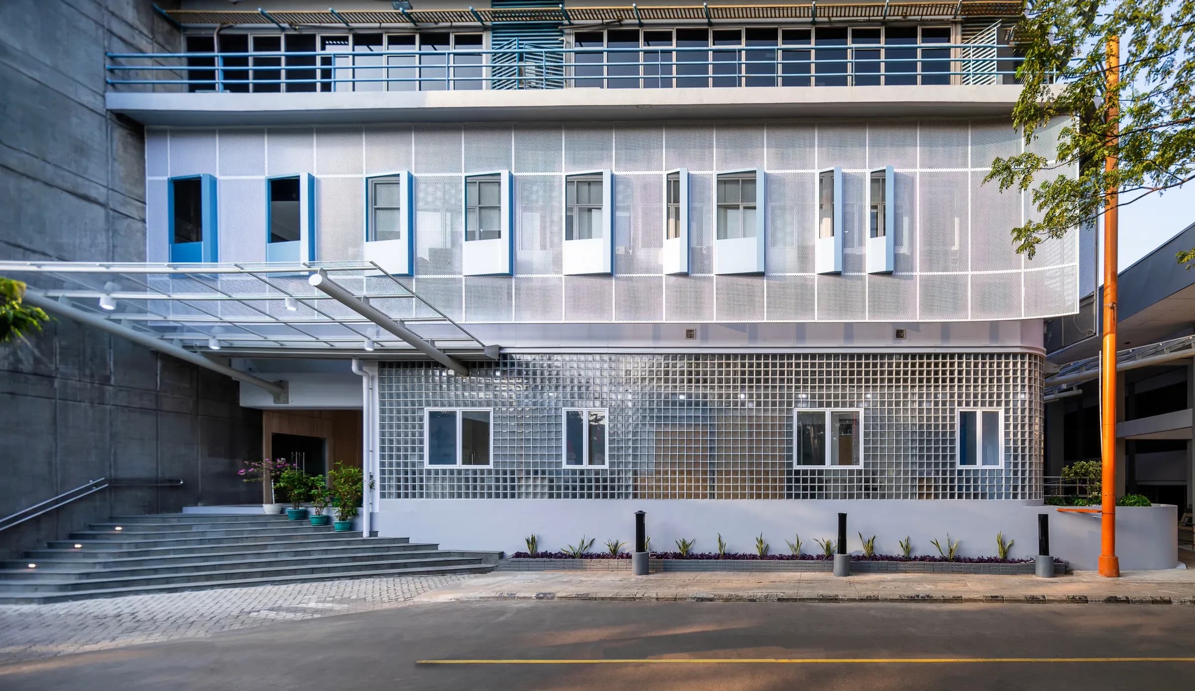 Building facade with perforated metal cladding and a glass block wall